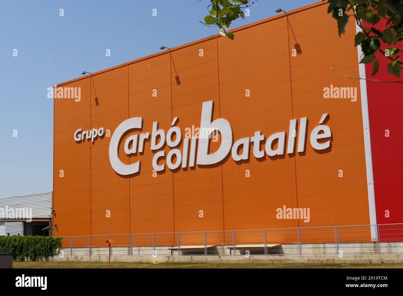 Barcellona, Spagna - 24 maggio 2023: L'audace facciata arancione dell'edificio Grupo Carboil Batalle si staglia contro un cielo azzurro e cristallino, che mette in mostra la comp Foto Stock