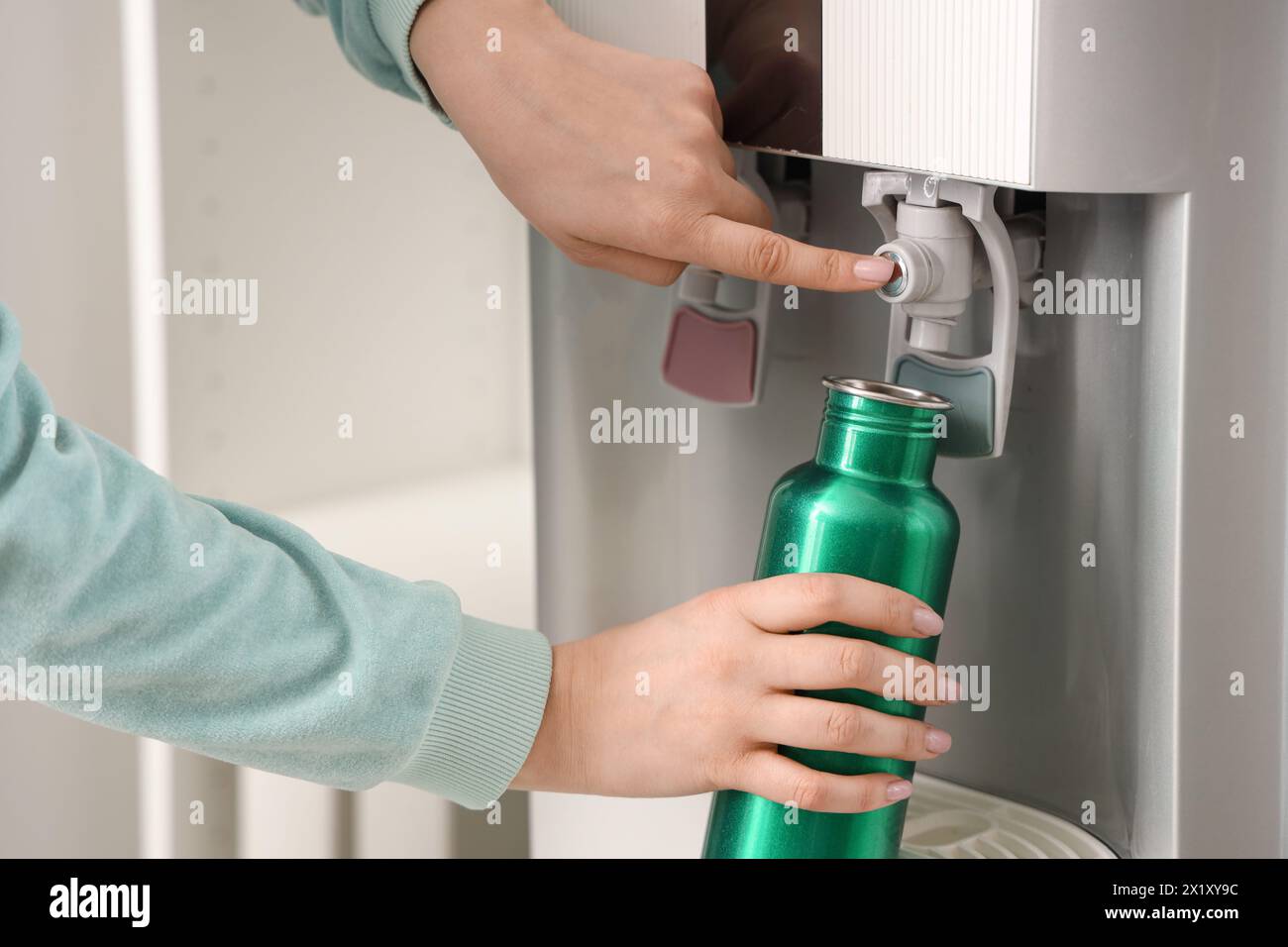 Bottiglia di riempimento mani femminili con acqua filtrata dal refrigeratore in camera Foto Stock