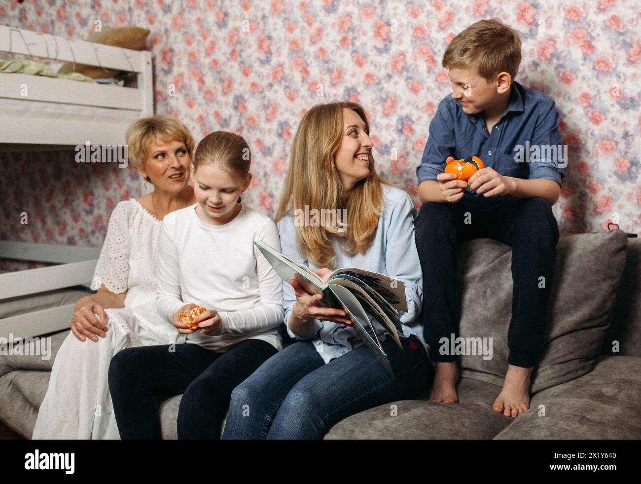 Un gruppo eterogeneo di persone è seduto a stretto contatto sulla sommità di un divano. Sembrano rilassati e impegnati in una conversazione, con vari expre Foto Stock