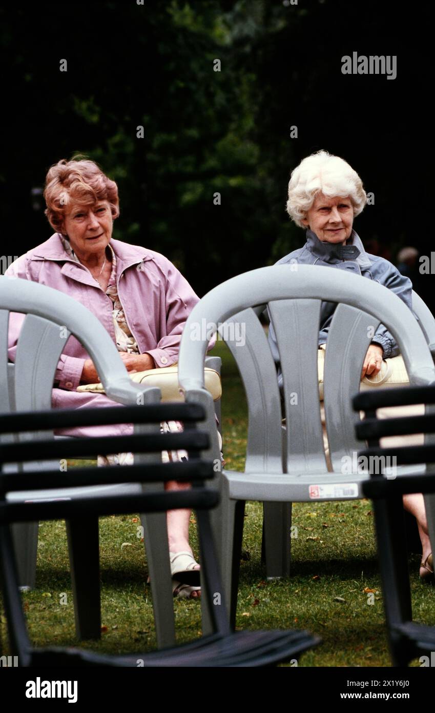 Due donne anziane guardano la banda di ottoni che suona musica in un palco del parco Foto Stock