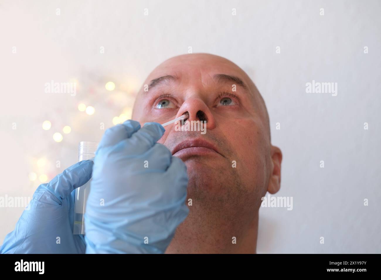 Faccia di un uomo calvo anziano primo piano, assistente di laboratorio, medico preleva un campione di tampone dalla mucosa nasale per il test del coronavirus, la determinazione del DNA Foto Stock