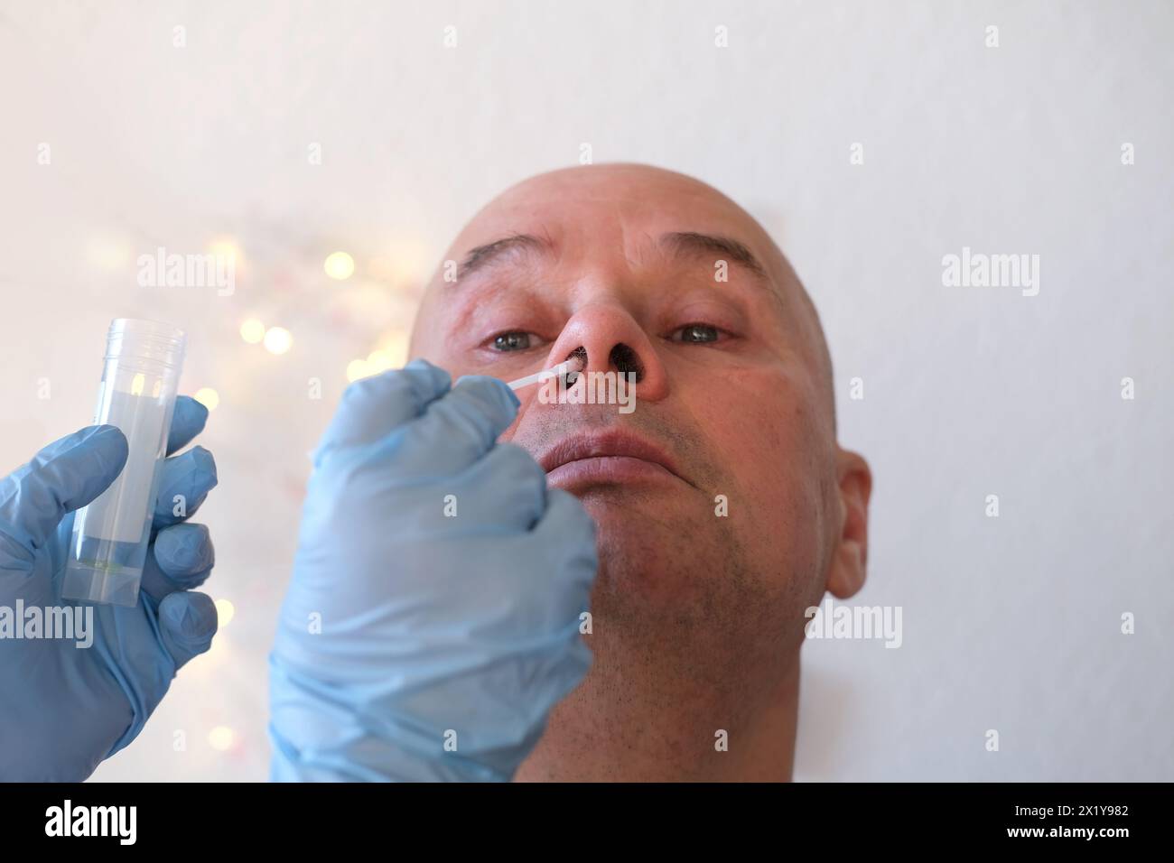 Faccia di un uomo calvo anziano primo piano, assistente di laboratorio, medico preleva un campione di tampone dalla mucosa nasale per il test del coronavirus, la determinazione del DNA Foto Stock