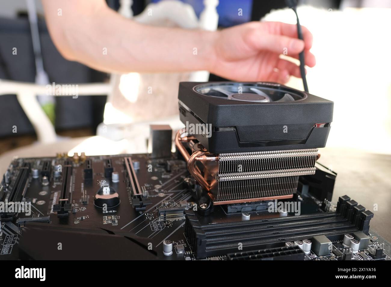 le mani di un giovane maschio installano un refrigeratore con tubi di calore in rame per il processore, altre parti del pc nel case, il concetto di riparazione delle apparecchiature, a. Foto Stock