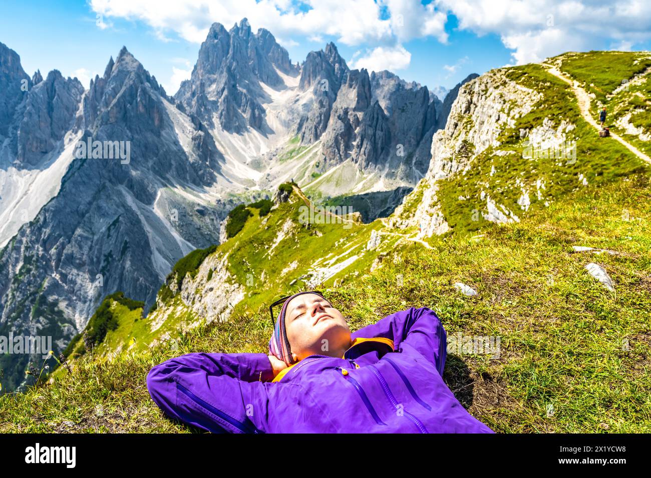 Descrizione: La giovane donna gode di un bagno di sole con vista epica sul gruppo dei Cadini di Misurina al mattino. Tre Cime, Dolomiti, alto Adige, Italia, E. Foto Stock