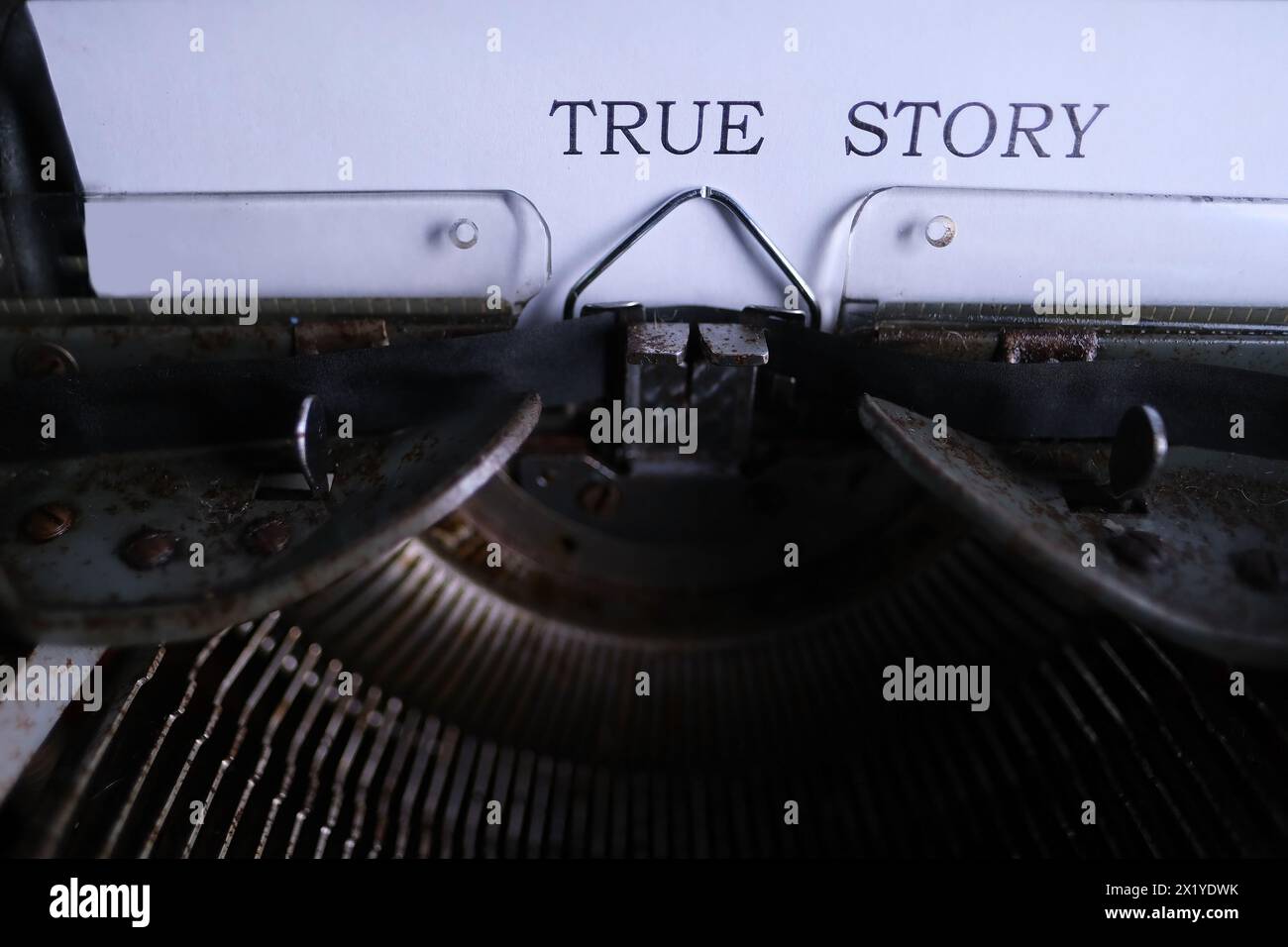 vecchia macchina da scrivere sul tavolo, le parole la storia vera sono stampate su carta in grande formato, stile retrò, concetto di scrittore, giornalista, detective privato Foto Stock