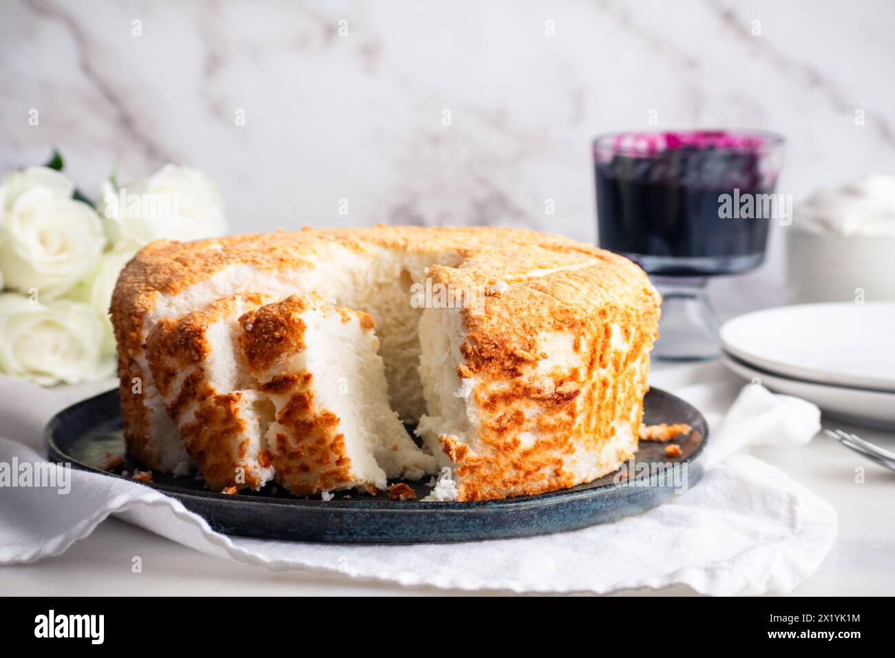 Torta Angel Food a fette con salsa ai mirtilli e panna montata: Fette di pan di Spagna servite con marmellata di mirtilli e crema chantilly a lato Foto Stock