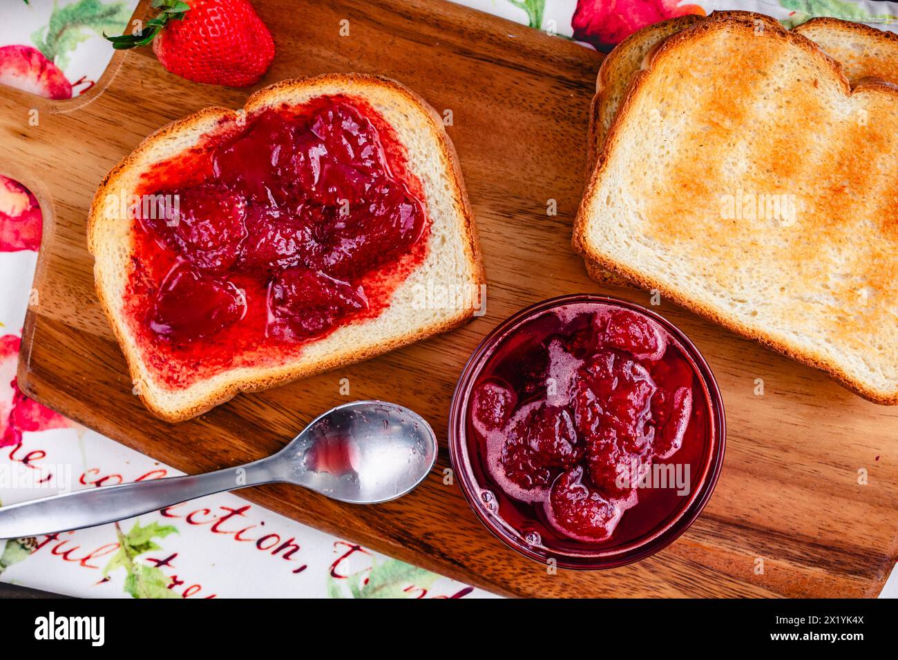 Fetta di pane tostato ricoperto da conserve di fragole fatte in casa: Pane bianco a fette e tostato e conserve di fragole fatte in casa con grandi pezzi di frutta Foto Stock
