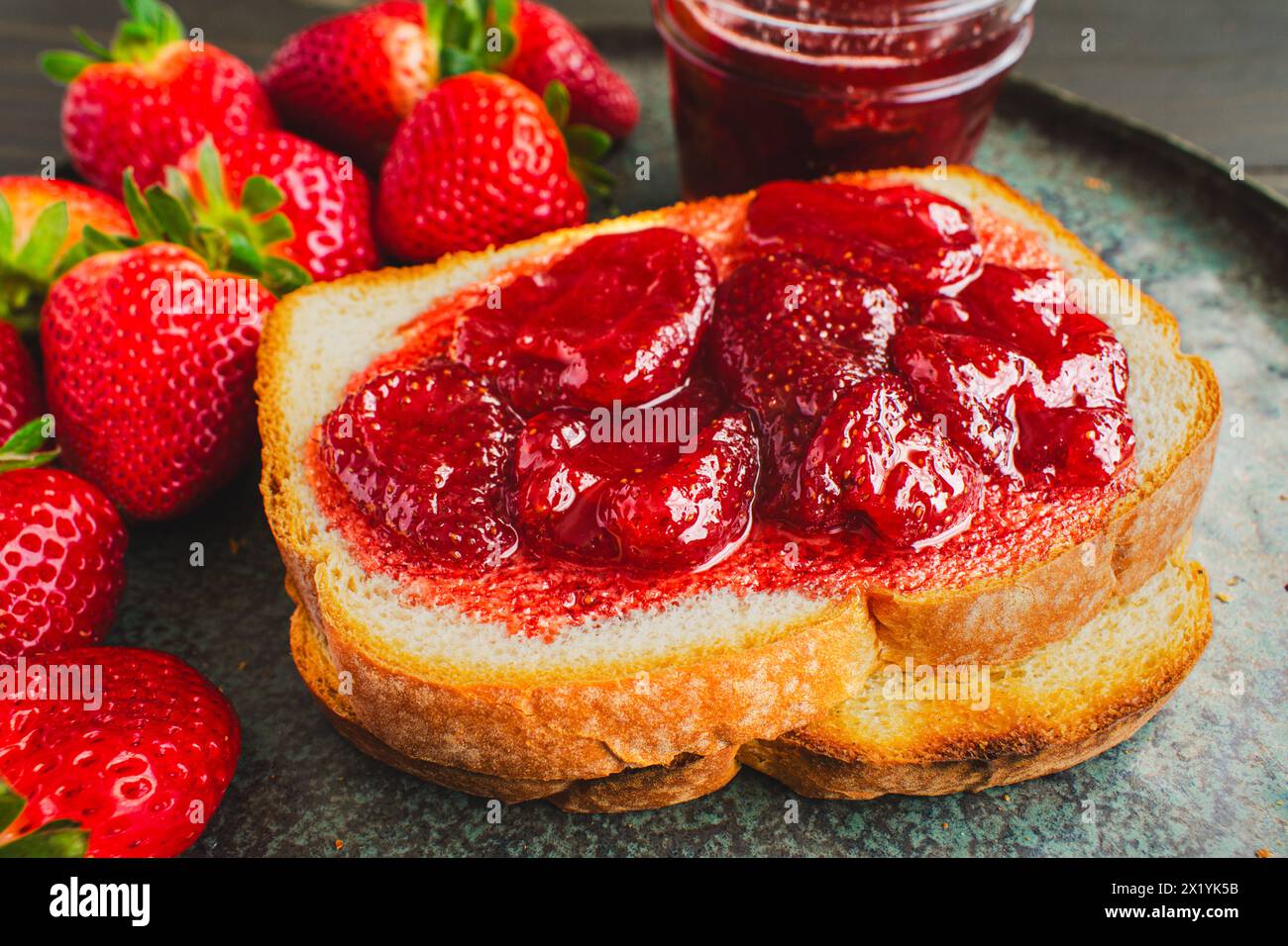 Fetta di pane tostato ricoperto da conserve di fragole fatte in casa: Pane bianco a fette e tostato e conserve di fragole fatte in casa con grandi pezzi di frutta Foto Stock