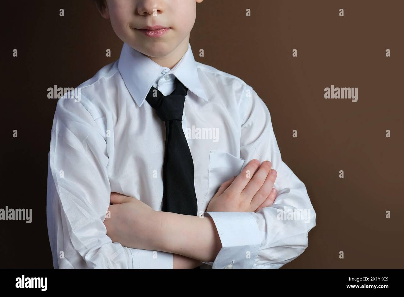 primo piano della parte inferiore della testa di un bambino di 6-7 anni, ragazzo con una camicia da lavoro bianca e cravatta sorridente, uniforme formale, concetto di un giovane autobus Foto Stock