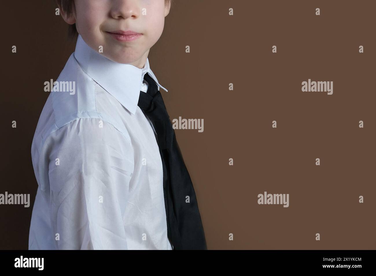 primo piano della parte inferiore della testa di un bambino di 6-7 anni, ragazzo con una camicia da lavoro bianca e cravatta sorridente, uniforme formale, concetto di un giovane autobus Foto Stock