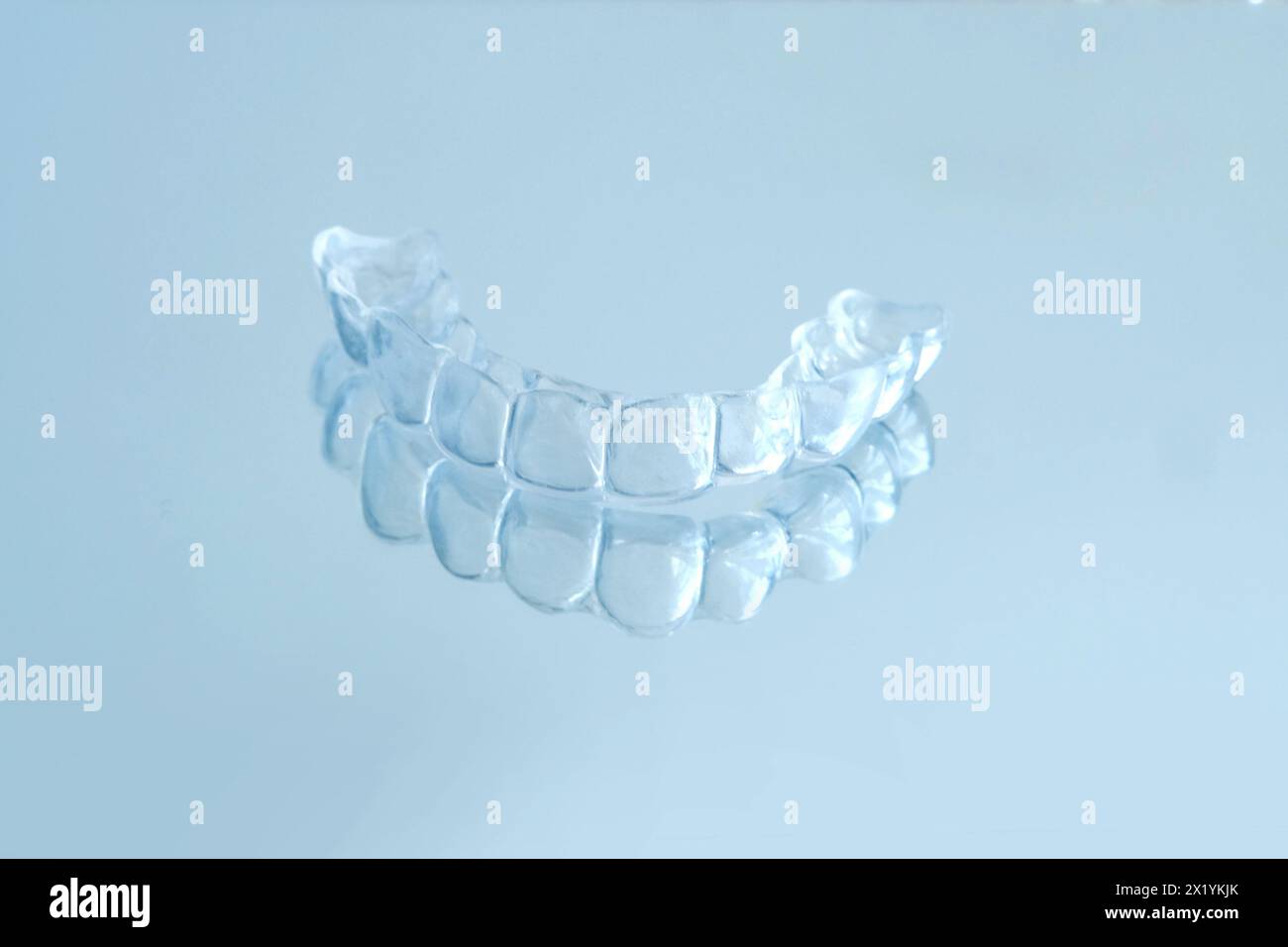 Primo piano di protezione per bocca notturna in silicone trasparente per stringere i denti smerigliatura dentaria supporto per il sonno su sfondo blu, servizi odontoiatrici concettuali, r Foto Stock