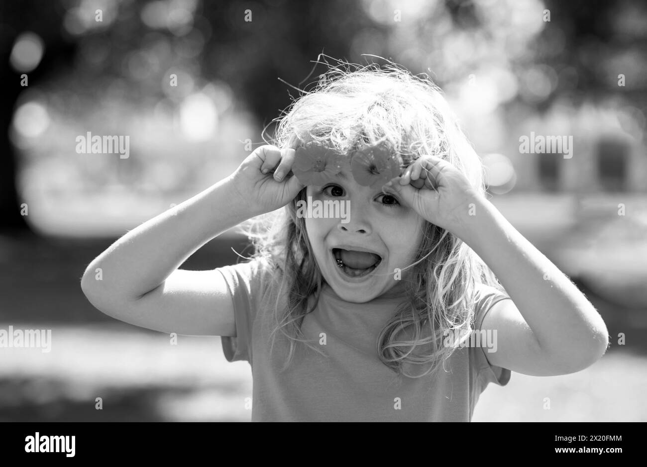 Carino bambino che raccoglie i fiori nel giardino estivo in fiore. Faccia bambino della molla. Bambino piccolo felice con fiori sull'erba in un'estate. Piccolo carino Foto Stock