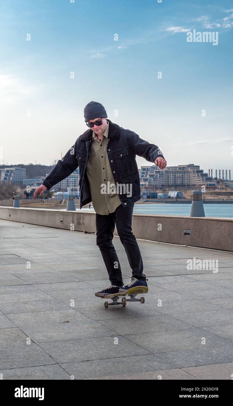 Giovane che cavalca uno skateboard facendo trucchi e salti Foto Stock