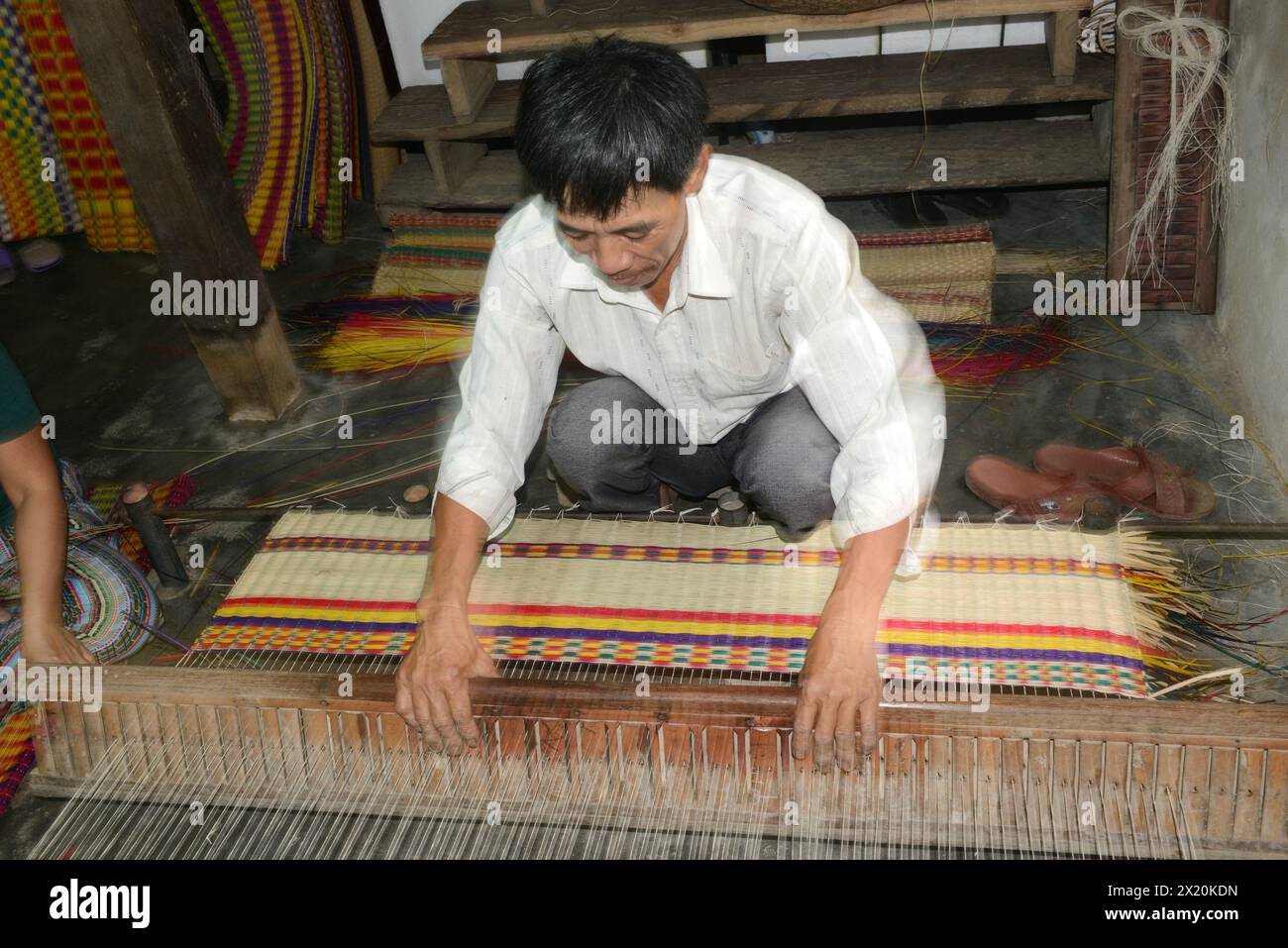 Un tessitore di tappeti che lavora nella sua casa in un piccolo villaggio a Cẩm Kim, Hội An, Vietnam. Foto Stock