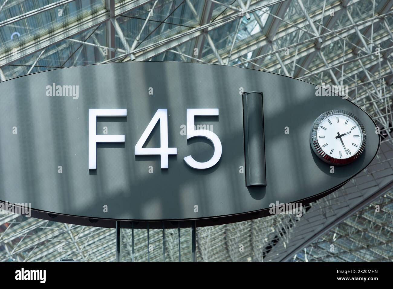 Moderno cartello aeroportuale F45 con orologio, che indica il cancello o la porta d'imbarco, situato in una struttura in acciaio e vetro presso l'aeroporto CDG di Parigi, Francia Foto Stock
