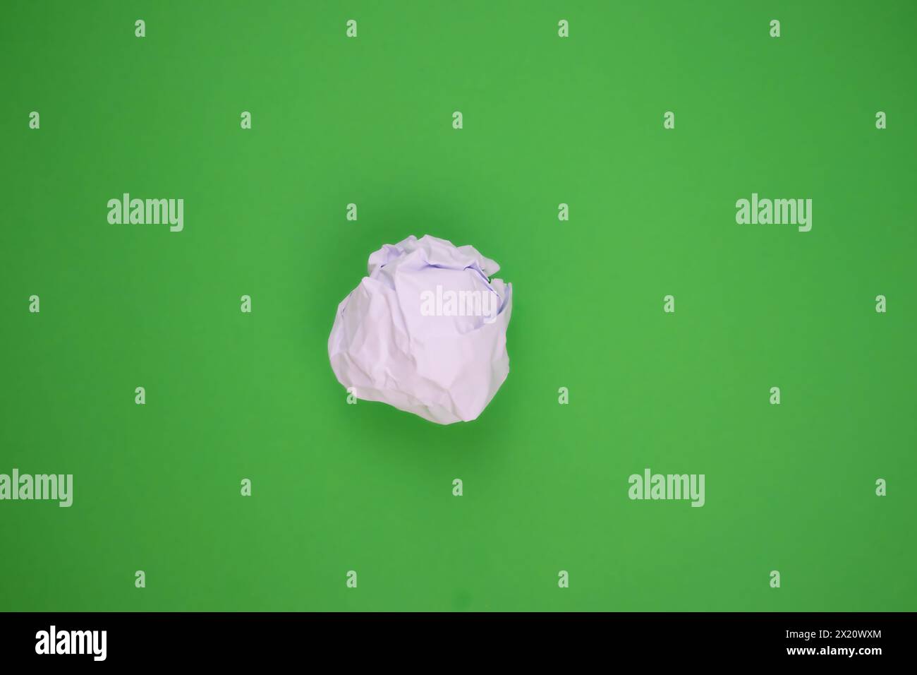 Carta bianca deformata su sfondo verde. Concetto di riciclaggio, simbolo di un concetto ecosostenibile. Foto Stock
