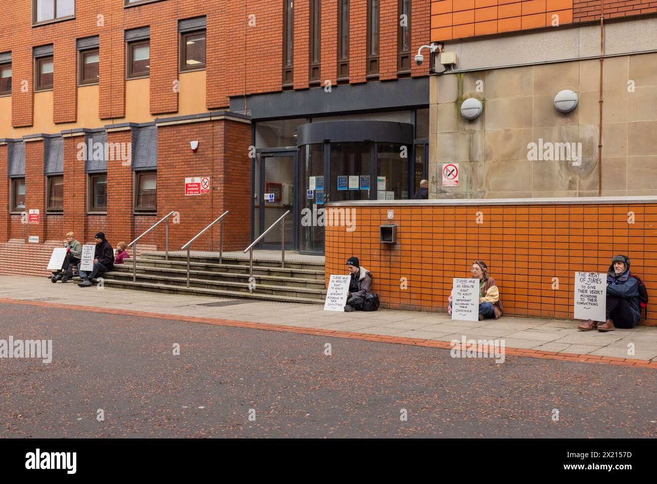 Leeds, Regno Unito. 19 APRILE, 2024. I manifestanti si riuniscono fuori dal tribunale combinato di Leeds come parte della protesta per difendere la nostra Juries dopo essersi riuniti per una fotografia i manifestanti si sono seduti su entrambi i lati dell'ingresso principale del tribunale e non hanno bloccato l'accesso. I manifestanti hanno tutti avuto lo stesso segno di “i giurati hanno il diritto assoluto di assolvere un imputato secondo la loro coscienza” come è stato visto con altre proteste prese in altri tribunali della corona in tutto il paese. Credito Milo Chandler/Alamy Live News Foto Stock