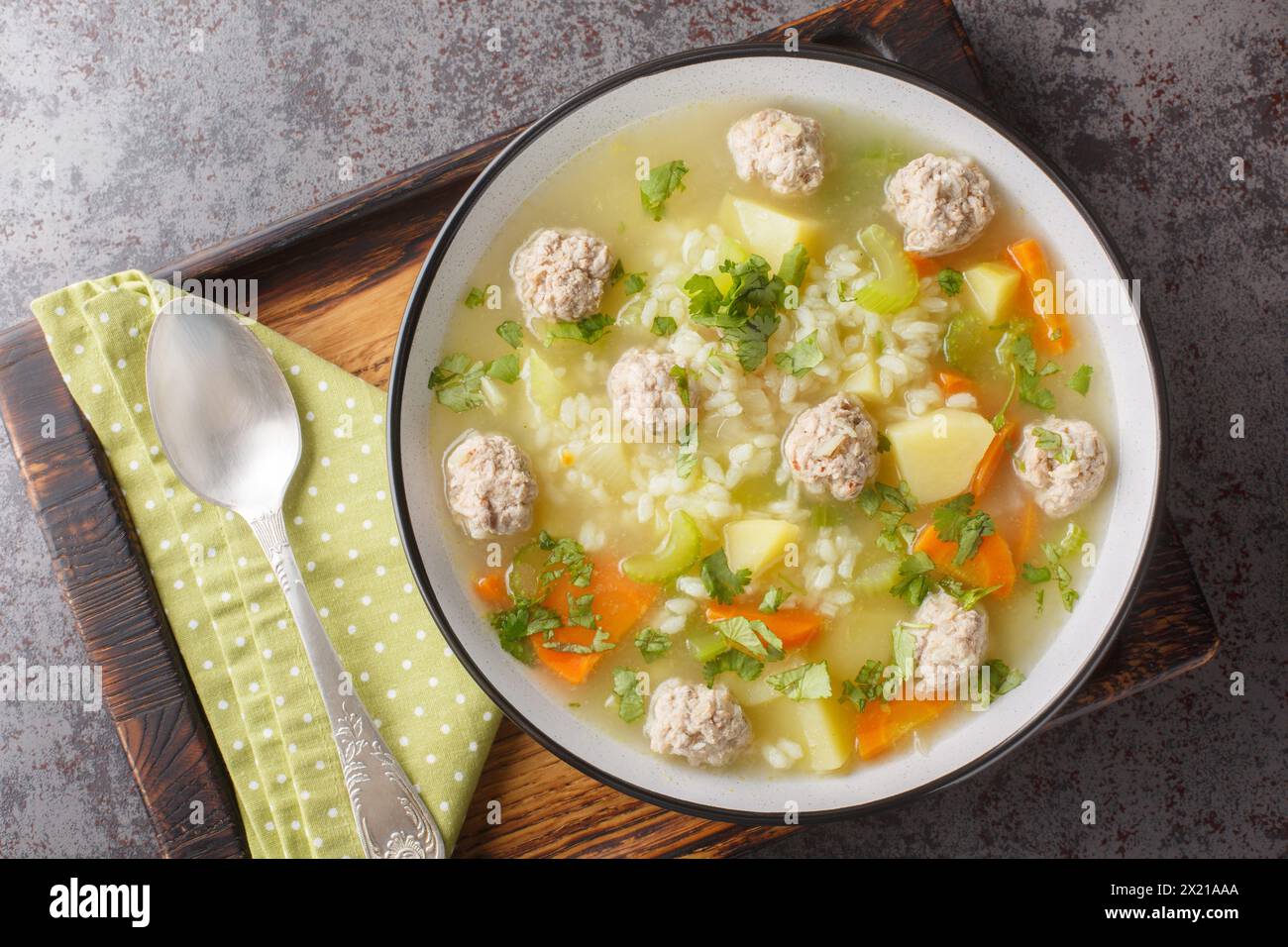 Zuppa dietetica di polpette di riso con sedano, carote, cipolle, patate ed erbe aromatiche da vicino in un recipiente sul tavolo. Vista dall'alto orizzontale Foto Stock
