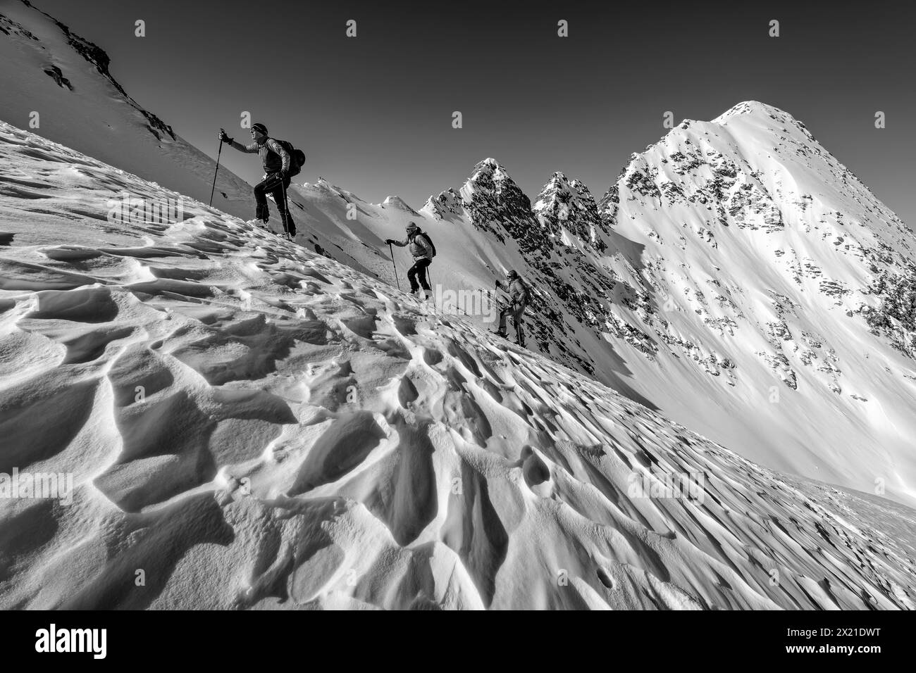 Tre persone in un tour sciistico scalano il Höllensteinkar attraverso il volo a vento, le Alpi della Zillertal, il Parco naturale delle Alpi della Zillertal, il Tirolo, l'Austria Foto Stock