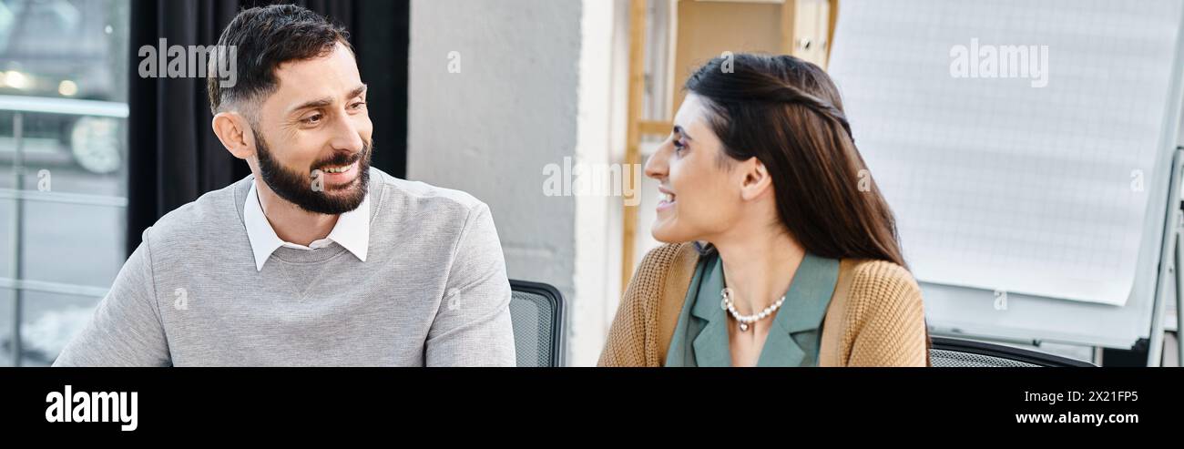 Un uomo e una donna sono seduti insieme su un autobus, coinvolti in una conversazione durante i loro spostamenti quotidiani per andare al lavoro. Foto Stock