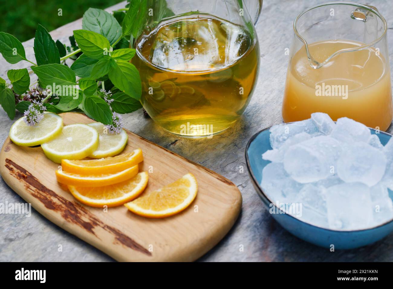 Tè freddo fatto in casa a base di tè alle erbe con succo di mela, succo d'arancia, menta d'acqua, maggiorana selvatica, fase 3: Fette d'arancia, fette di limone e ghiaccio sono adde Foto Stock