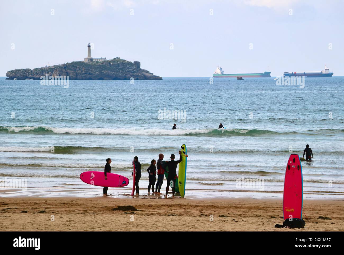 Lezioni di surf di gruppo in un pomeriggio tranquillo con navi da carico ancorate all'orizzonte e spiaggia di Mouro Island Somo Ribamontán al Mar Cantabria Spagna Foto Stock