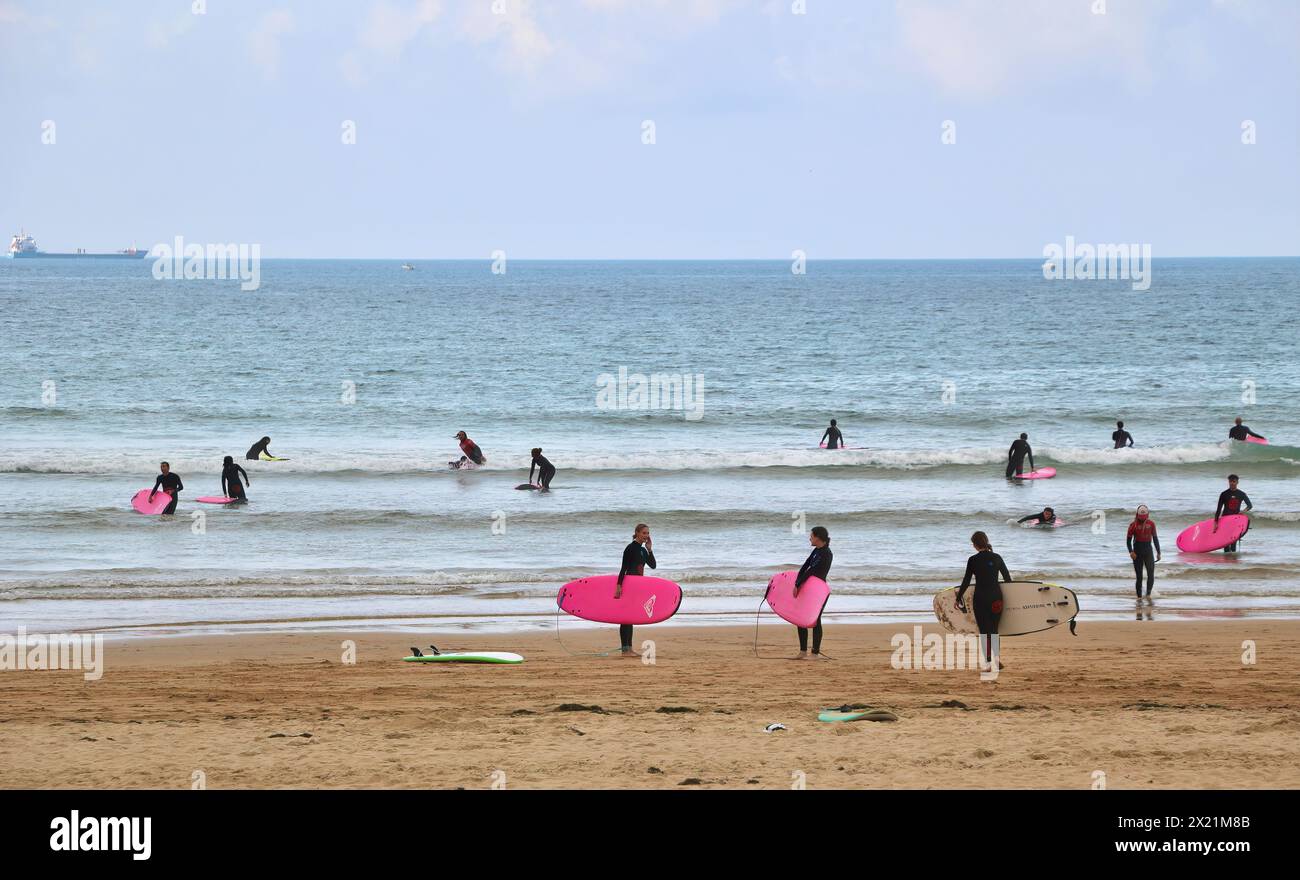 Lezioni di surf di gruppo in un tranquillo pomeriggio di settembre con una nave cargo ancorata all'orizzonte sulla spiaggia di Somo Ribamontán al Mar Cantabria, Spagna Foto Stock