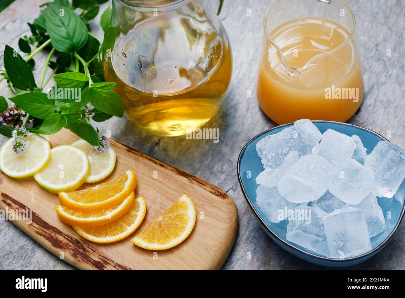 Tè freddo fatto in casa a base di tè alle erbe con succo di mela, succo d'arancia, menta d'acqua, maggiorana selvatica, fase 3: Fette d'arancia, fette di limone e ghiaccio sono adde Foto Stock