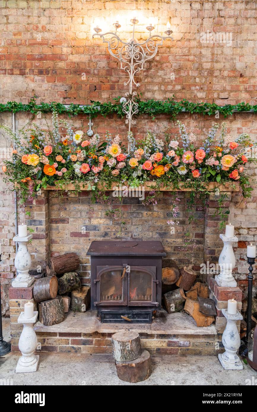 Un caminetto con decorazioni floreali per una cerimonia di nozze presso la Botley Hill Farm nel Surrey, Regno Unito Foto Stock