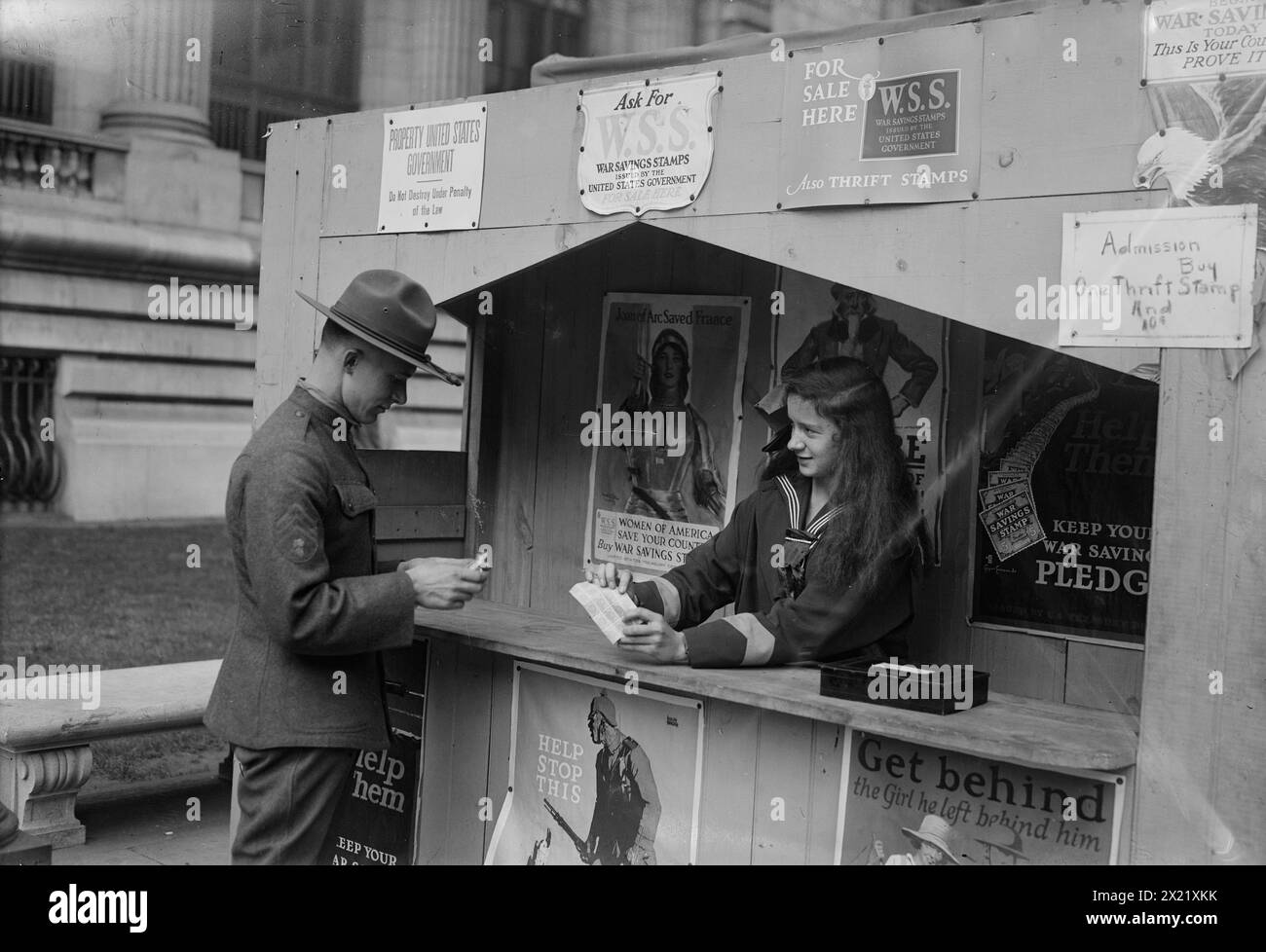Sally Hamlin, tra c1915 e c1920. Sally Hamlin (1902-1987) in uno stand War Saving Stamps decorato con poster della prima guerra mondiale. Un soldato si trova accanto alla cabina. Foto Stock