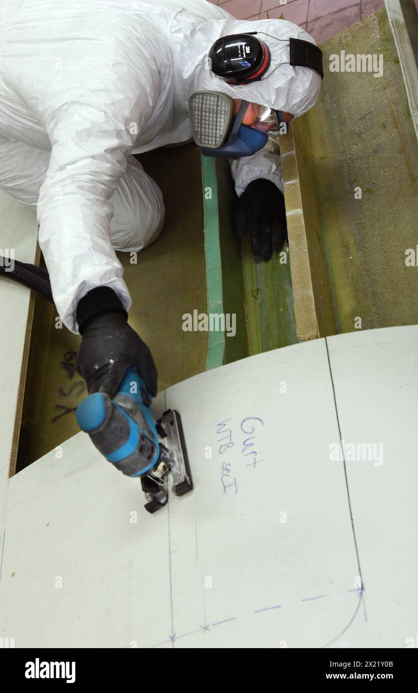 12 aprile 2024, Sassonia, Lipsia: Nel centro tecnico del campus dell'Università di Scienze applicate (HTWK), l'assistente di ricerca Dimitrij Seibert del team guidato dal professore HTWK di costruzione leggera con materiali compositi il Prof. Dr. Robert Böhm prepara un segmento lungo 4,3 metri di una lunghezza di 19,3 metri, pala del rotore della turbina eolica di circa 25 anni fa per un test per determinarne le proprietà meccaniche. I test fanno parte di EuReCOMP, un progetto di ricerca collaborativa finanziato dall'UE che mira a sviluppare metodi sostenibili per il riciclaggio e il riutilizzo di materiali compositi provenienti da eolici Foto Stock