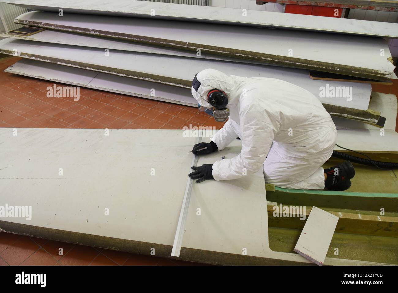 12 aprile 2024, Sassonia, Lipsia: Nel centro tecnico del campus dell'Università di Scienze applicate (HTWK), l'assistente di ricerca Dimitrij Seibert del team guidato dal professore HTWK di costruzione leggera con materiali compositi il Prof. Dr. Robert Böhm prepara un segmento lungo 4,3 metri di una lunghezza di 19,3 metri, pala del rotore della turbina eolica di circa 25 anni fa per un test per determinarne le proprietà meccaniche. I test fanno parte di EuReCOMP, un progetto di ricerca collaborativa finanziato dall'UE che mira a sviluppare metodi sostenibili per il riciclaggio e il riutilizzo di materiali compositi provenienti da eolici Foto Stock