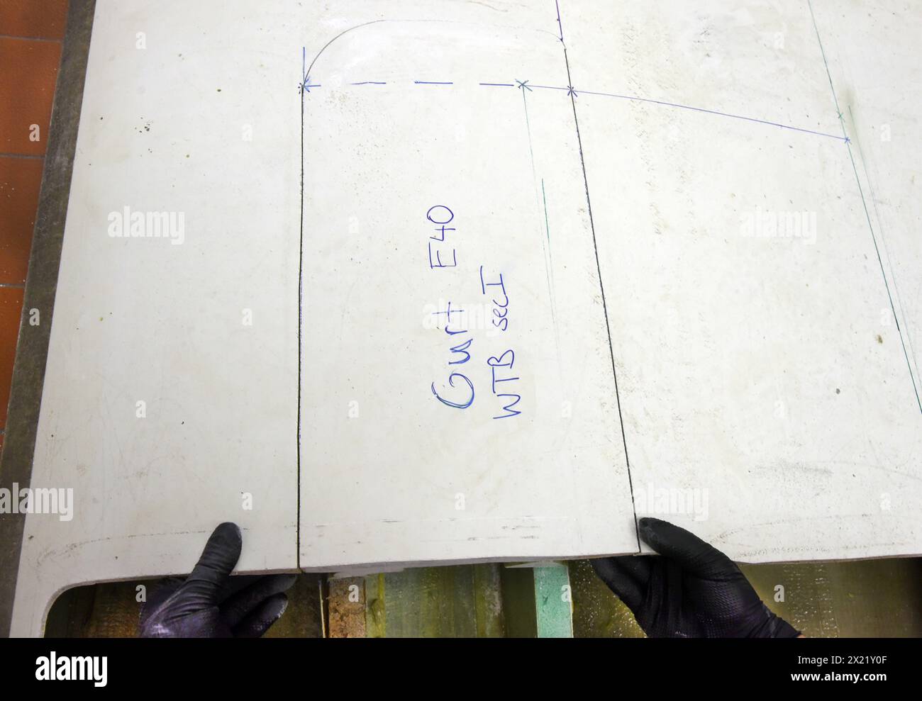 12 aprile 2024, Sassonia, Lipsia: Nel centro tecnico del campus dell’Università di scienze applicate (HTWK), l'assistente alla ricerca Dimitrij Seibert del team guidato dal professore HTWK di costruzione leggera con materiali compositi Robert Böhm prepara una parte di una pala del rotore della turbina eolica di 25 anni smontata per una prova delle sue proprietà meccaniche. Le indagini fanno parte di EuReCOMP, un progetto di ricerca collaborativa finanziato dall'UE che mira a sviluppare metodi sostenibili per il riciclaggio e il riutilizzo di materiali compositi provenienti da componenti dell'energia eolica, tra l'altro. Scienziati Foto Stock