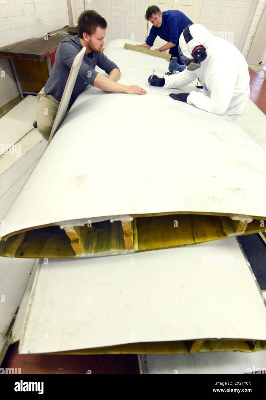12 aprile 2024, Sassonia, Lipsia: Nel centro tecnico del campus dell'Università di scienze applicate (HTWK), gli assistenti alla ricerca Philipp Johst (a sinistra) e Dimitrij Seibert (a destra) preparano un segmento lungo 4,3 metri di lunghezza di 19,3 metri, pala del rotore di una turbina eolica di circa 25 anni fa per un test per determinare le sue proprietà meccaniche con HTWK Professor of Lightweight Construction with Composite Materials Prof. Dr. Robert Böhm. I test fanno parte di EuReCOMP, un progetto di ricerca collaborativa finanziato dall'UE che mira a sviluppare metodi sostenibili per il riciclaggio e il riutilizzo del compagno composito Foto Stock