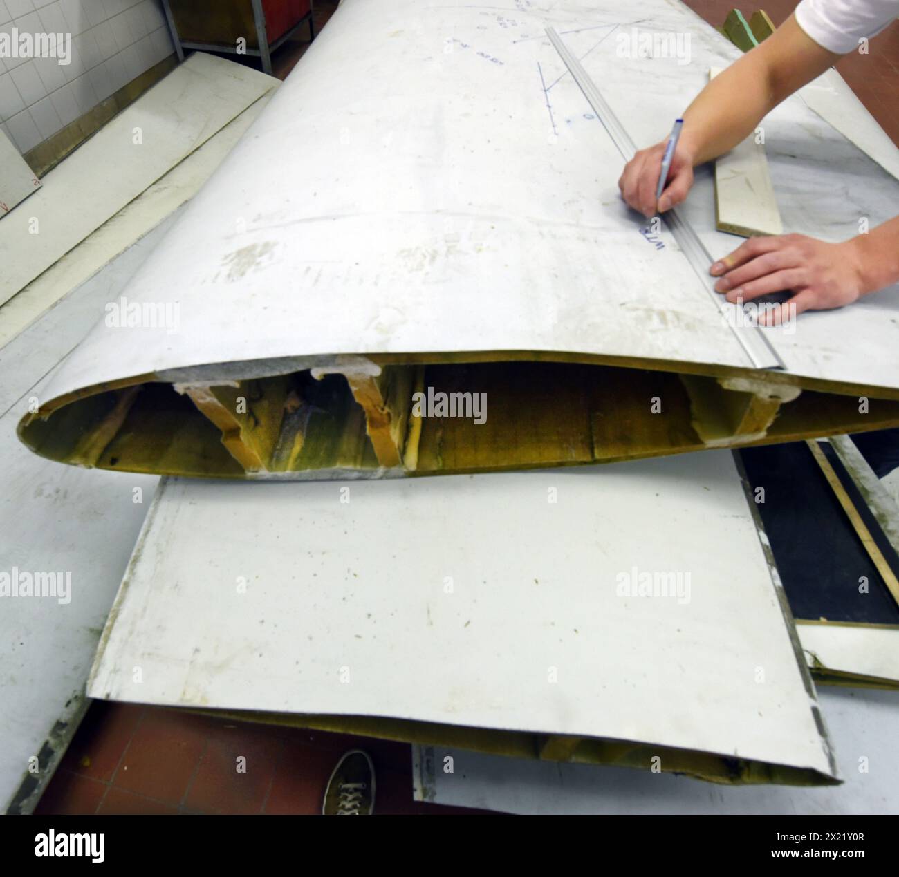 12 aprile 2024, Sassonia, Lipsia: Nel centro tecnico del campus dell’Università di scienze applicate (HTWK), l'assistente alla ricerca Dimitrij Seibert del team guidato dal professore HTWK di costruzione leggera con materiali compositi Robert Böhm prepara una parte di una pala del rotore della turbina eolica di 25 anni smontata per una prova delle sue proprietà meccaniche. Le indagini fanno parte di EuReCOMP, un progetto di ricerca collaborativa finanziato dall'UE che mira a sviluppare metodi sostenibili per il riciclaggio e il riutilizzo di materiali compositi provenienti da componenti dell'energia eolica, tra l'altro. Scienziati Foto Stock