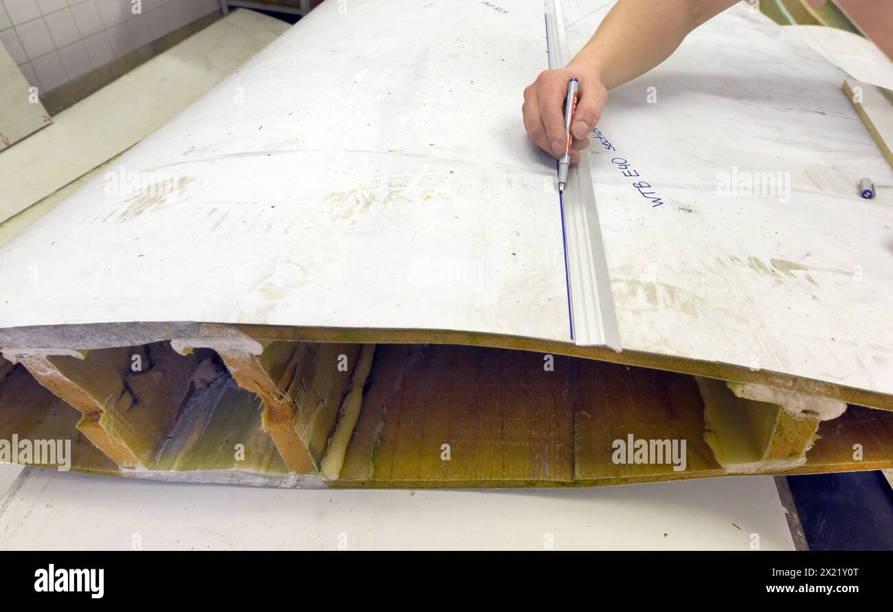 12 aprile 2024, Sassonia, Lipsia: Nel centro tecnico del campus dell’Università di scienze applicate (HTWK), l'assistente alla ricerca Dimitrij Seibert del team guidato dal professore HTWK di costruzione leggera con materiali compositi Robert Böhm prepara una parte di una pala del rotore della turbina eolica di 25 anni smontata per una prova delle sue proprietà meccaniche. Le indagini fanno parte di EuReCOMP, un progetto di ricerca collaborativa finanziato dall'UE che mira a sviluppare metodi sostenibili per il riciclaggio e il riutilizzo di materiali compositi provenienti da componenti dell'energia eolica, tra l'altro. Scienziati Foto Stock