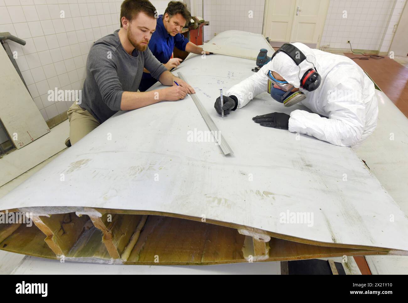 12 aprile 2024, Sassonia, Lipsia: Nel centro tecnico del campus dell'Università di scienze applicate (HTWK), gli assistenti alla ricerca Philipp Johst (a sinistra) e Dimitrij Seibert (a destra) preparano un segmento lungo 4,3 metri di lunghezza di 19,3 metri, pala del rotore di una turbina eolica di circa 25 anni fa per un test per determinare le sue proprietà meccaniche con HTWK Professor of Lightweight Construction with Composite Materials Prof. Dr. Robert Böhm. I test fanno parte di EuReCOMP, un progetto di ricerca collaborativa finanziato dall'UE che mira a sviluppare metodi sostenibili per il riciclaggio e il riutilizzo del compagno composito Foto Stock