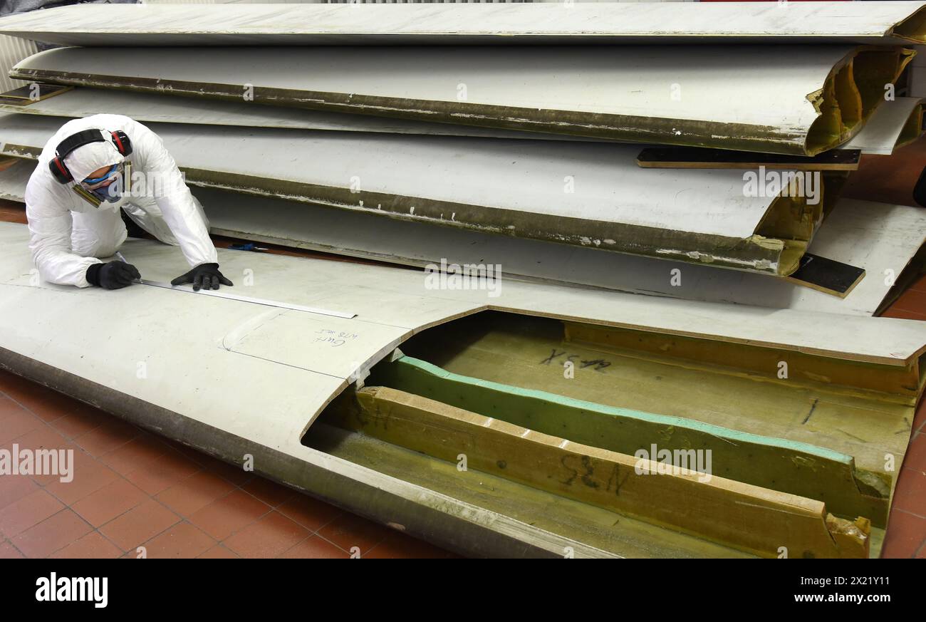 12 aprile 2024, Sassonia, Lipsia: Nel centro tecnico del campus dell'Università di Scienze applicate (HTWK), l'assistente di ricerca Dimitrij Seibert del team guidato dal professore HTWK di costruzione leggera con materiali compositi il Prof. Dr. Robert Böhm prepara un segmento lungo 4,3 metri di una lunghezza di 19,3 metri, pala del rotore della turbina eolica di circa 25 anni fa per un test per determinarne le proprietà meccaniche. I test fanno parte di EuReCOMP, un progetto di ricerca collaborativa finanziato dall'UE che mira a sviluppare metodi sostenibili per il riciclaggio e il riutilizzo di materiali compositi provenienti da eolici Foto Stock