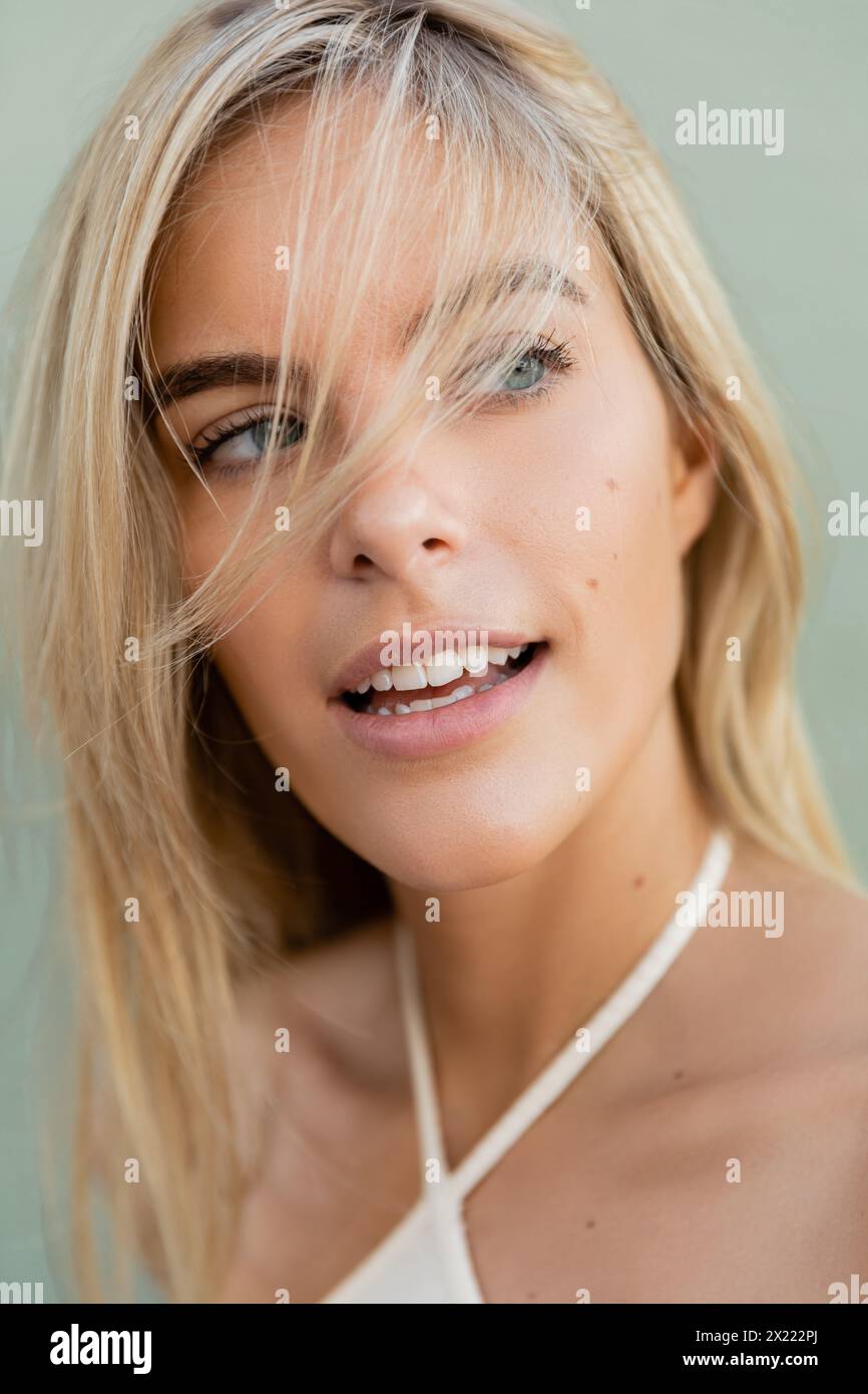 Una giovane e bella donna bionda a Miami sorride, indossando un top bianco in una giornata di sole. Foto Stock