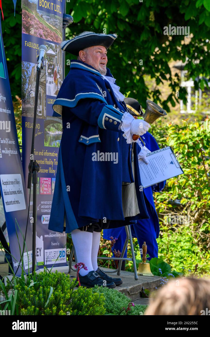 Uomo pigrillo e fattorino (livrea e vestiti blu) che fanno annunci e annunci pubblici rumorosi - Ilkley, West Yorkshire, Inghilterra, Regno Unito. Foto Stock