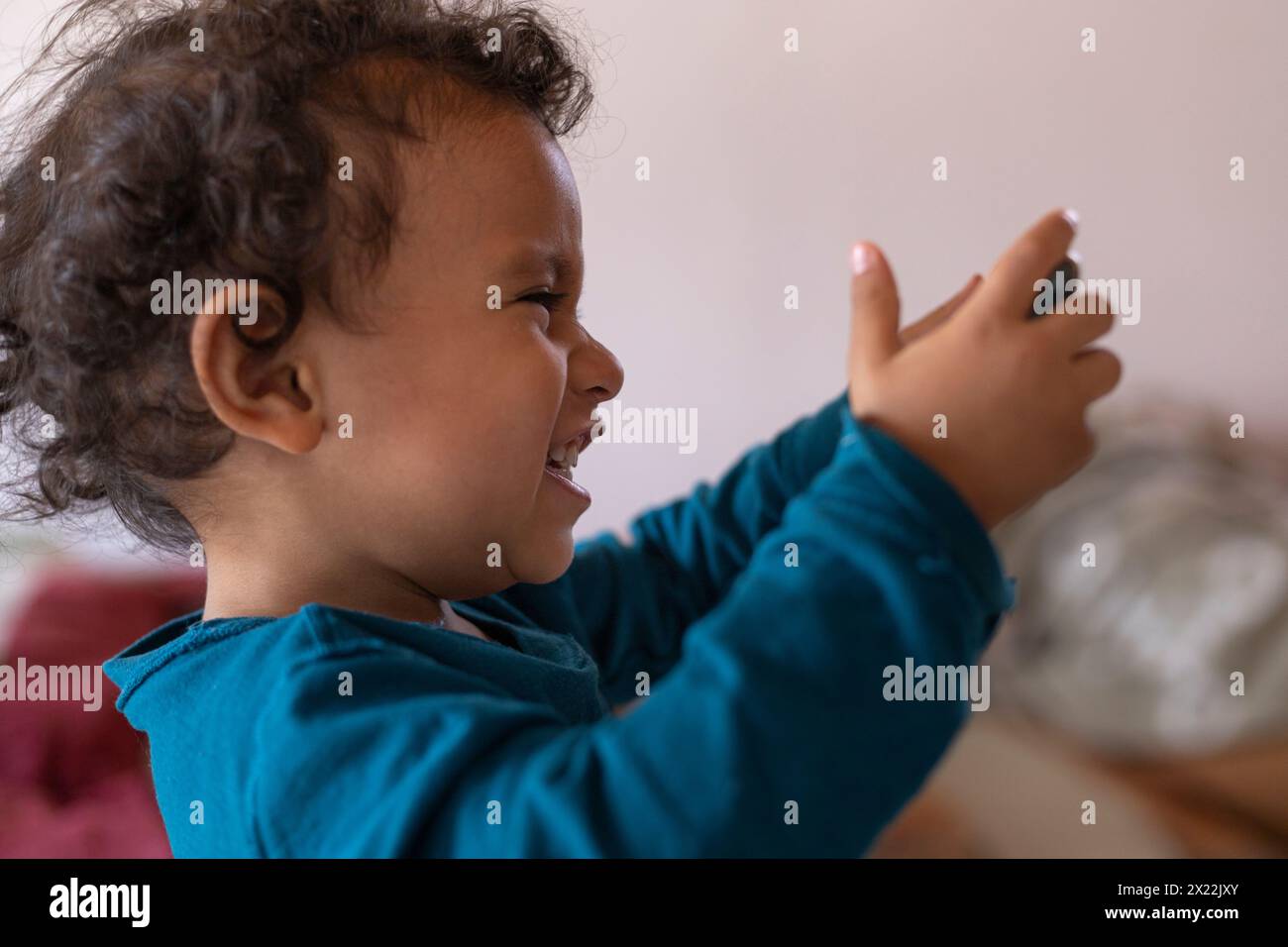 Il ragazzo latino-americano (2) si diverte a usare il cellulare di sua madre imitando il fotografo che lo sta fotografando. Concetto di infanzia e apprendimento. Foto Stock
