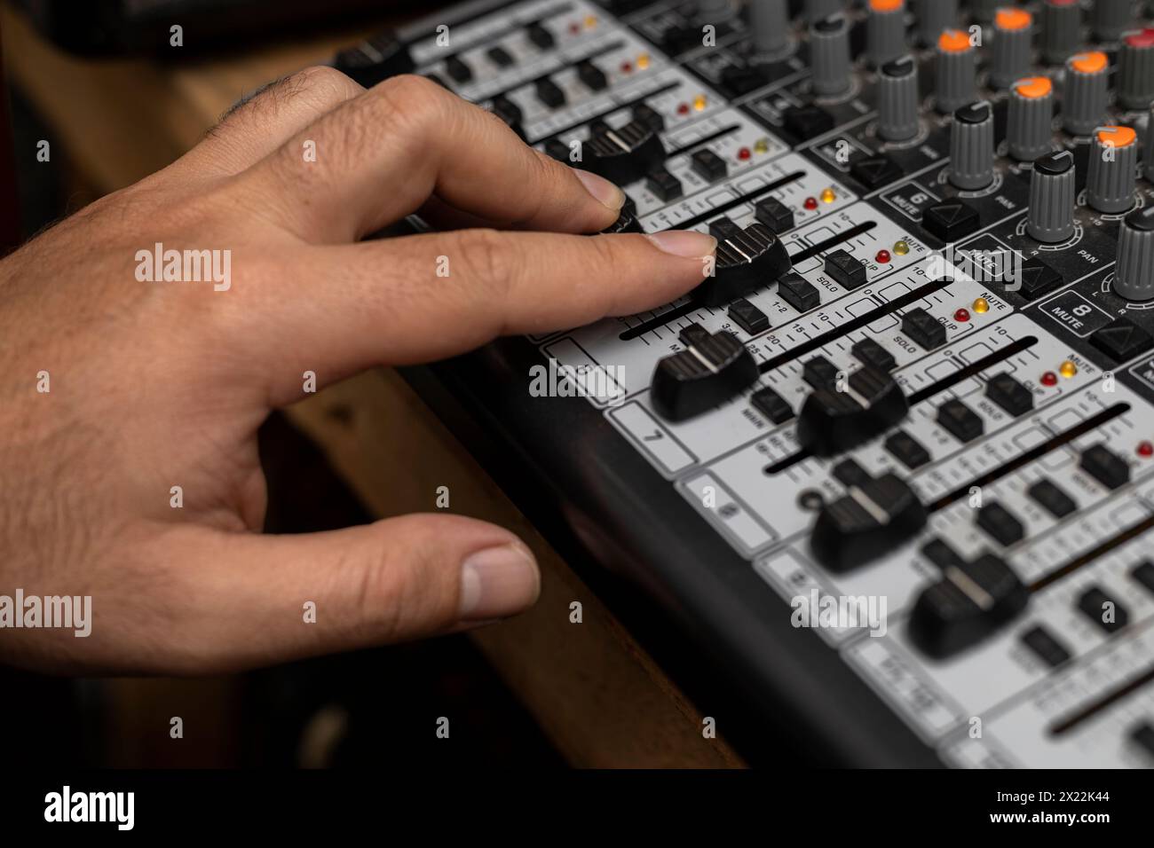Primo piano di una mano maschio che cambia volume sulla piastra di miscelazione. Creazione di musica, concetto dj Foto Stock