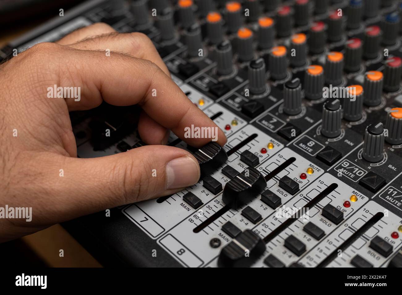 Primo piano di una mano maschio che cambia volume sulla piastra di miscelazione. Creazione di musica, concetto dj Foto Stock