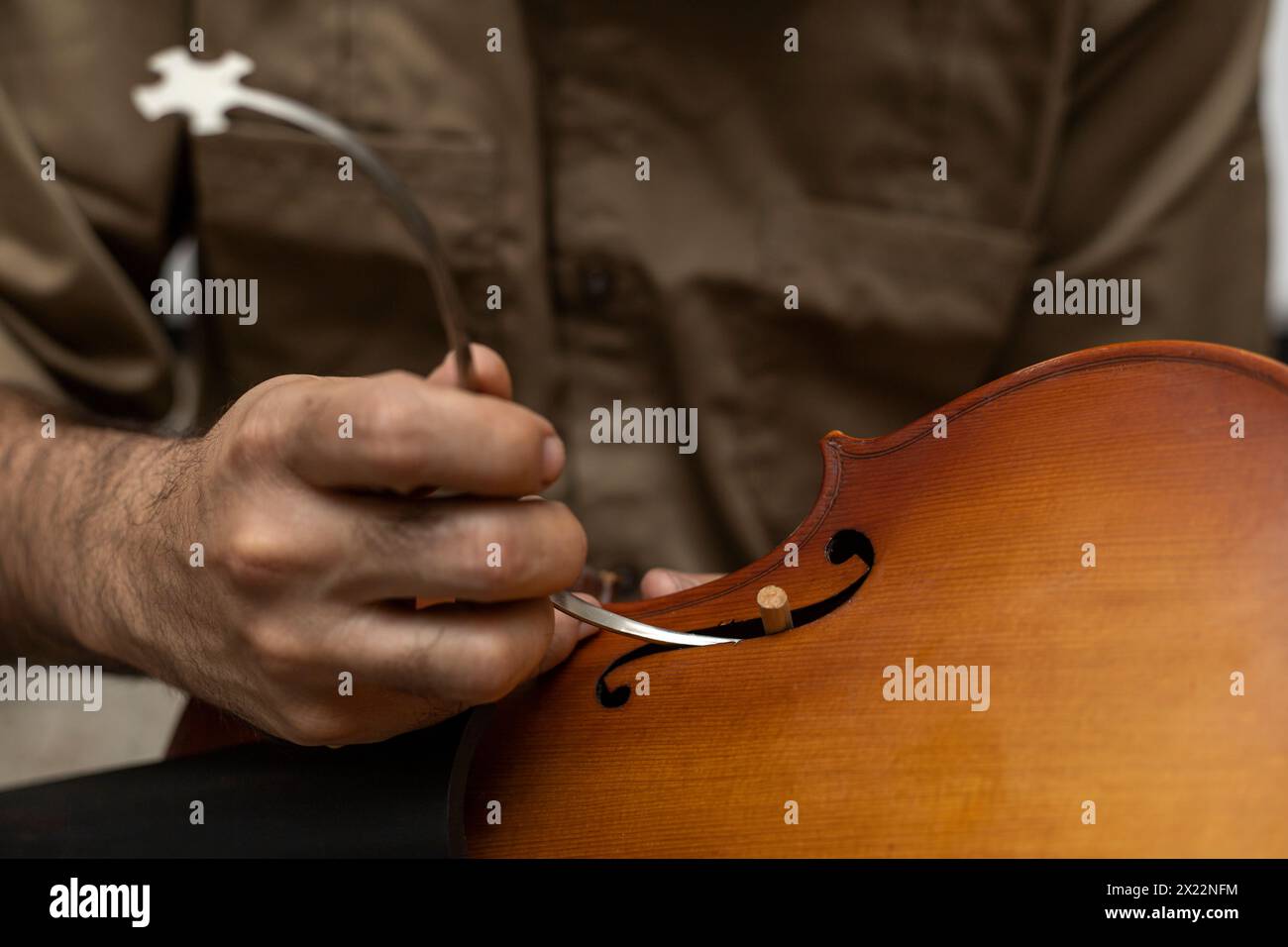 Liutaio latinoamericano che colloca un palo sonoro tra la parte superiore e la parte inferiore del violino. Strumenti a corda Foto Stock