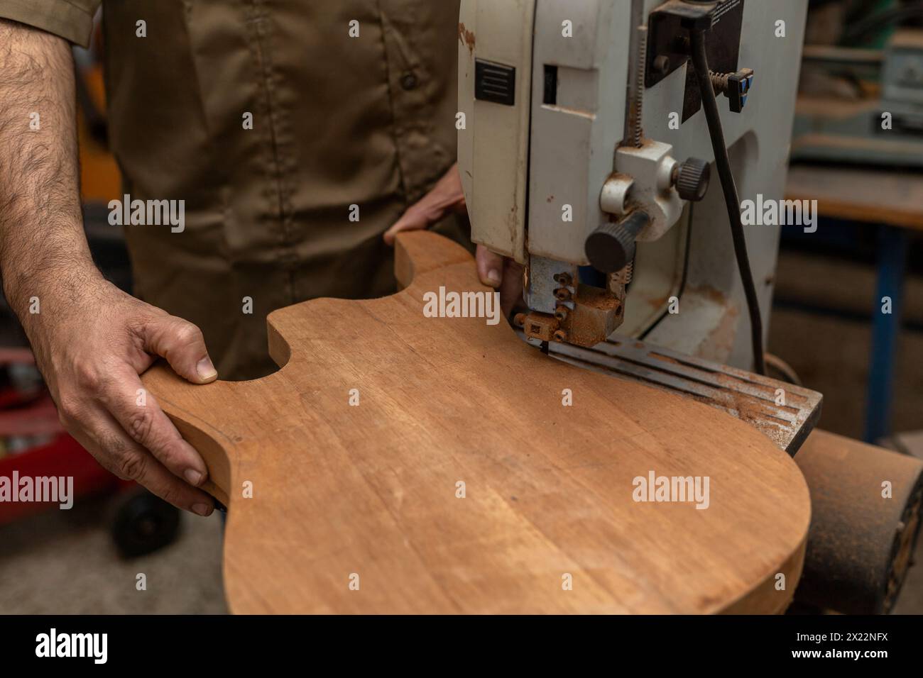 Primo piano dell'irriconoscibile liutaio latinoamericano che produce una chitarra elettrica con una sega. Concetto di costruzione dello strumento a corde Foto Stock