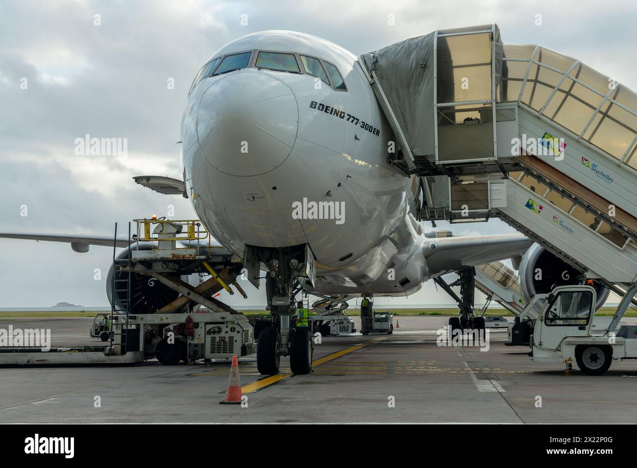 Vista frontale di un aereo Boeing 777 con un ponte d'imbarco parcheggiato sull'asfalto di un aeroporto, in attesa dei passeggeri Foto Stock