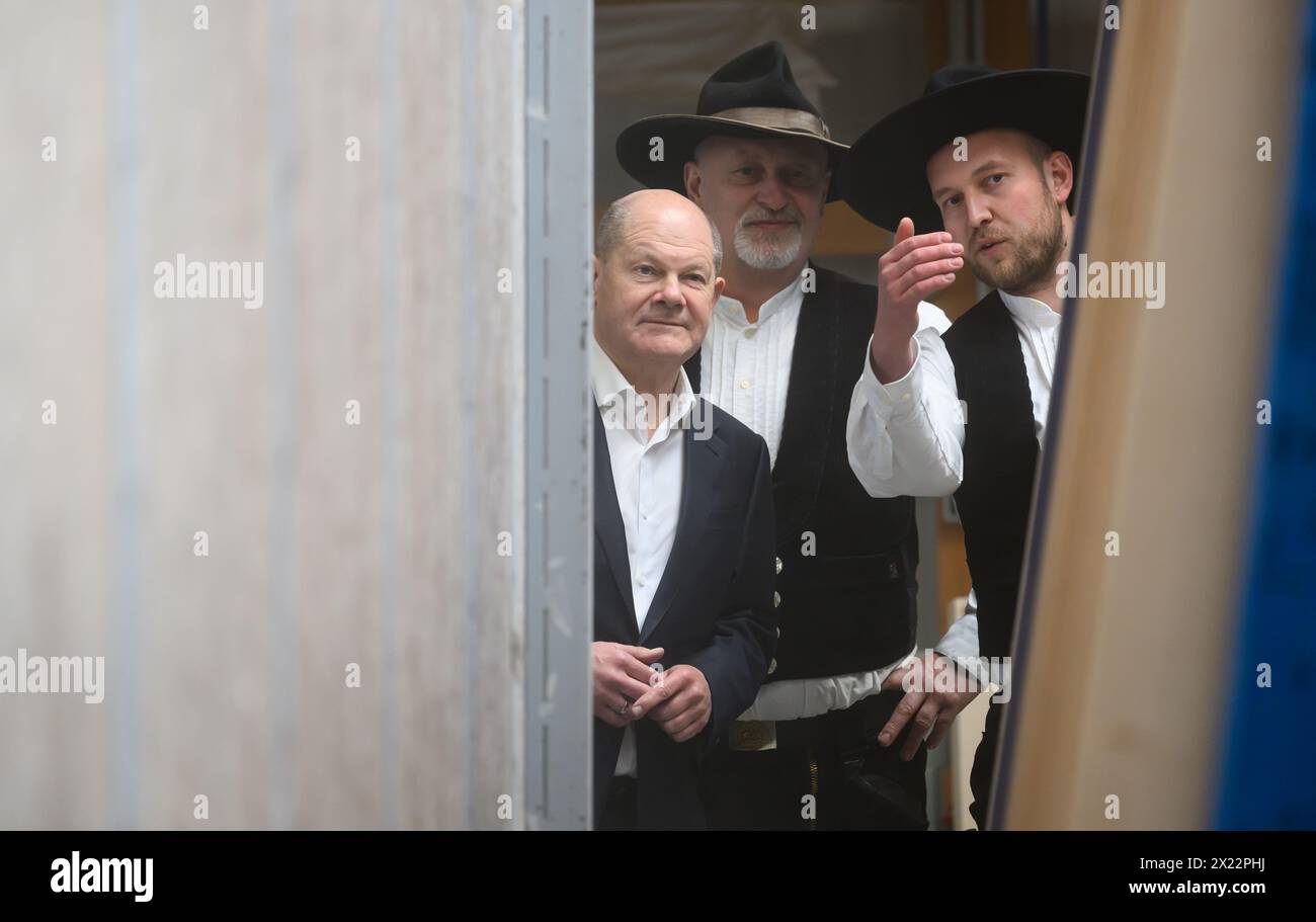 Dresda, Germania. 19 aprile 2024. Il Cancelliere federale Olaf Scholz (SPD, l) ha i maestri falegnami Ralf Lepski (2° da sinistra) e Felix Lepski spiegano il processo di produzione durante la sua visita ad una società di costruzioni in legno di Dresda. Scholz si unisce al presidente della Confederazione tedesca dell'artigianato qualificato (ZDH) e al presidente della camera di Dresda dell'artigianato qualificato in un tour dei laboratori e parla con i dipendenti dell'azienda delle questioni attuali nel settore dell'artigianato specializzato. Crediti: Robert Michael/dpa/Alamy Live News Foto Stock