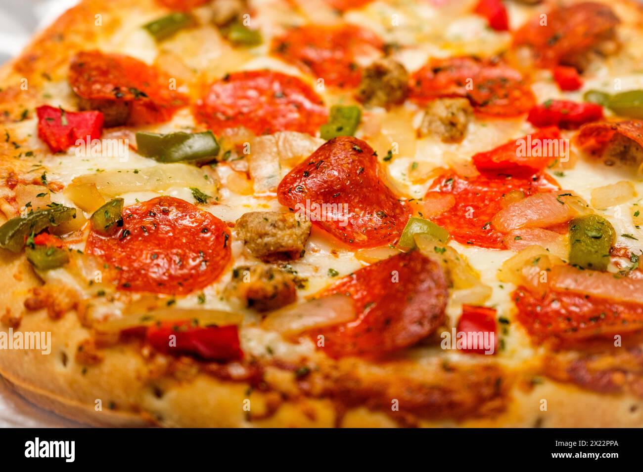 Primo piano con pizza al peperoni. Un delizioso fast food appena sfornato con impasto, formaggio, salsa di pomodoro e condimenti come prodotti gastronomici e vege. Foto Stock