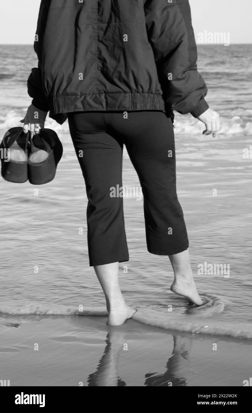 Una donna in cappotto cammina a Hunting Island, South Carolina Foto Stock