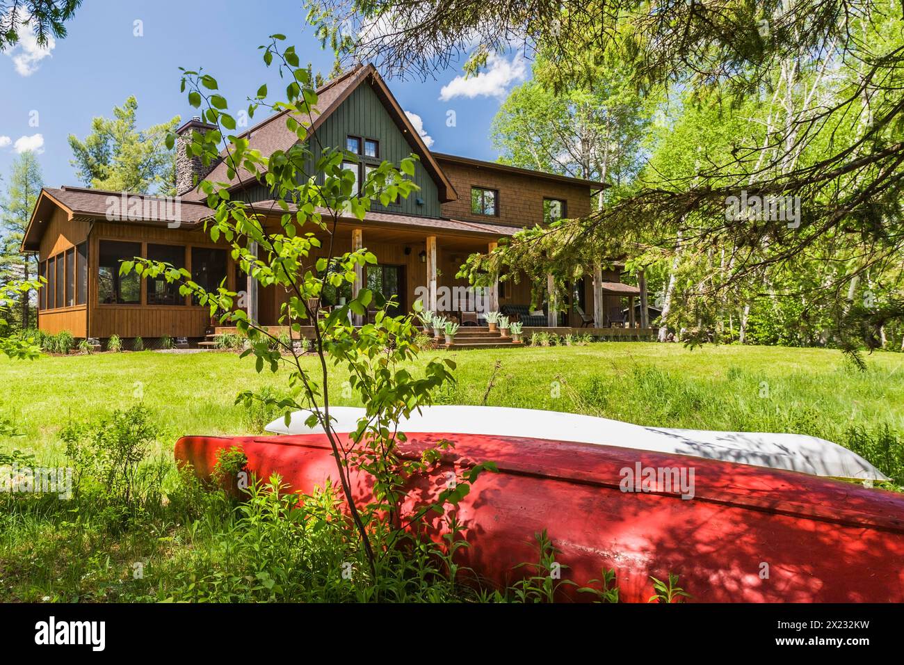 Vista posteriore di legno di abete rosso e verde e rivestimento in legno di cedro certificato LEED Country Home con veranda a fine primavera, Quebec, Canada Foto Stock